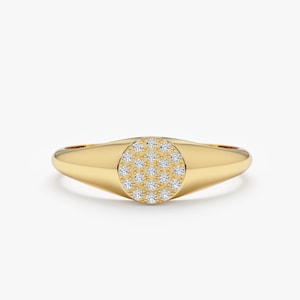 May include: A gold signet ring with a round pave diamond setting.