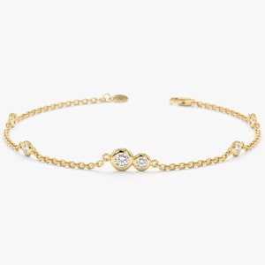 May include: A gold chain bracelet with five bezel-set round diamonds. The diamonds are clustered in the center of the bracelet.
