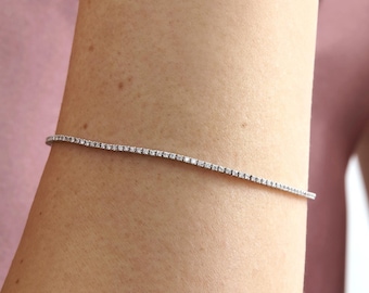 Puede incluir: Un brazalete de tenis plateado con pequeñas piedras de circonita cúbica transparentes.