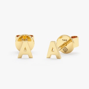 May include: A pair of gold initial earrings featuring the letter 'A'. The earrings are made of 14k gold and have a simple, minimalist design.