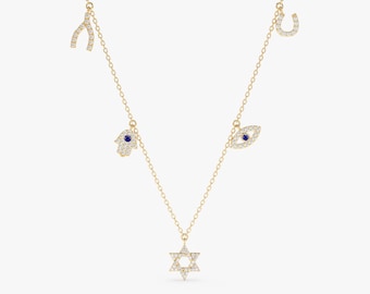 May include: A gold chain necklace with five charms: a horseshoe, a wishbone, a hamsa hand, an evil eye, and a Star of David. All charms are adorned with clear and blue crystals.