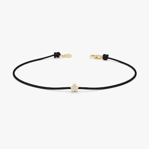 May include: A black string bracelet with a small gold star charm set with clear diamonds.