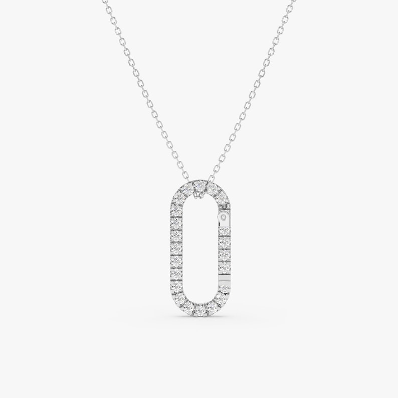 May include: A silver chain necklace with a diamond-encrusted oval pendant. The pendant is shaped like a sideways 'O' with a small diamond in the center.