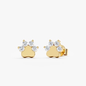 May include: A pair of gold paw print earrings with small clear cubic zirconia stones.