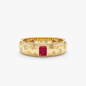 Op de afbeelding: Een 14K gouden ring met een centrale smaragdgeslepen rode edelsteen. Het oppervlak is gegraveerd met hemelse motieven zoals sterren en maansikkels, afgewisseld met kleine ronde witte stenen. De binnenzijde is gestempeld met 14K.
