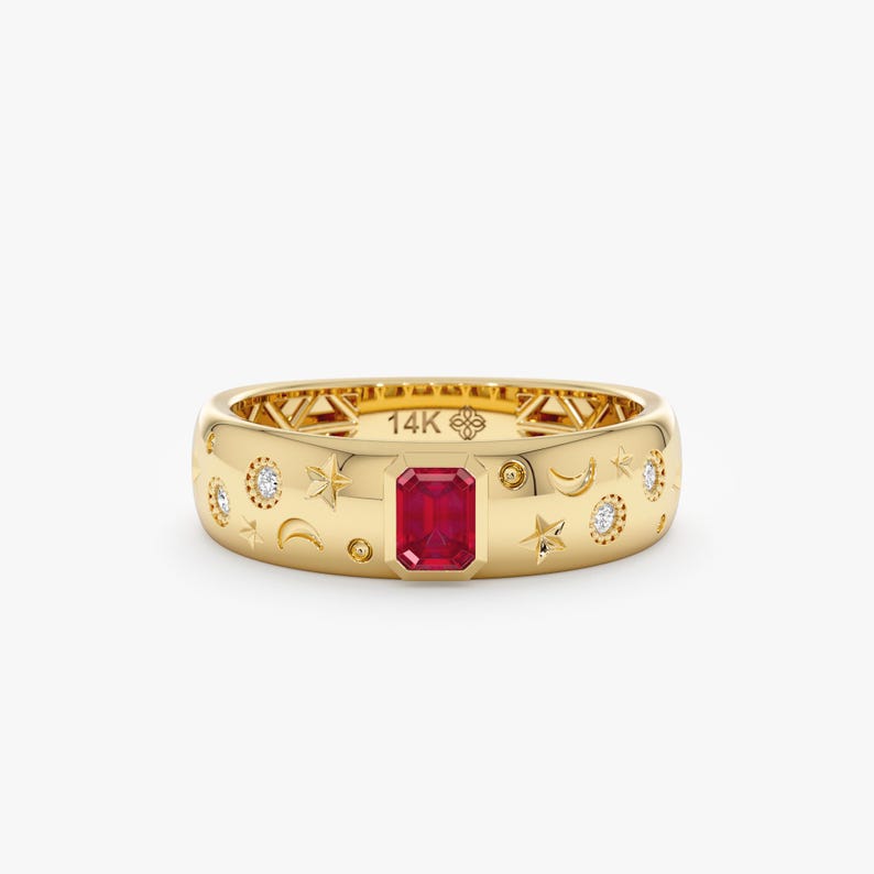Op de afbeelding: Een 14K gouden ring met een centrale smaragdgeslepen rode edelsteen. Het oppervlak is gegraveerd met hemelse motieven zoals sterren en maansikkels, afgewisseld met kleine ronde witte stenen. De binnenzijde is gestempeld met 14K.