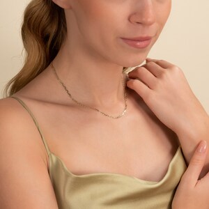 May include: A delicate gold chain necklace with a simple, classic design. The chain is thin and has a subtle shine.