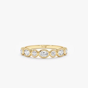 May include: A gold ring with a series of clear, round and oval-cut gemstones. The ring is set in a yellow gold band. The ring is on a white background. The ring is a piece of jewelry.