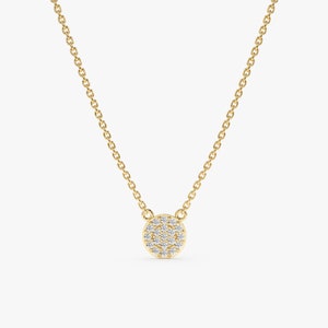 May include: A delicate gold chain necklace with a small round pendant set with tiny sparkling diamonds.