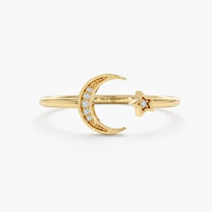 May include: A gold ring featuring a crescent moon design with small diamonds and a star with a single diamond.