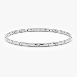 Puede incluir: Un brazalete de plata con detalles de diamantes en forma de estrella. El brazalete tiene una superficie lisa y pulida con un dise&ntilde;o delicado y estampado en el borde superior. Los diamantes est&aacute;n espaciados uniformemente.