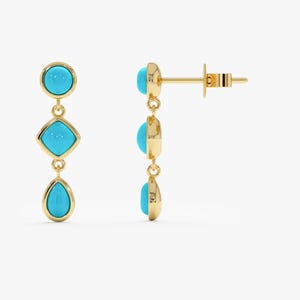 May include: A pair of gold-colored drop earrings with turquoise-colored stones. Each earring features three stones: a circle, a square, and a teardrop shape. The earrings are displayed against a white background.
