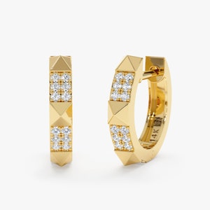 Puede incluir: Aretes de aro de oro con un diseño adornado con diamantes y un acento en forma de pirámide. Los aretes están marcados con "14K".