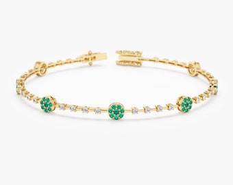May include: A gold bangle bracelet with a row of small round emerald green stones and a row of small round clear stones.
