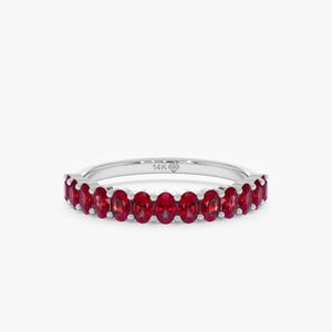 K&ouml;nnte beinhalten: Ein silberner Ring mit einer Reihe oval geschliffener, leuchtend roter Edelsteine. Der Ring ist mit "14K" markiert und hat ein filigranes Design, das die Farbe und den Glanz der Edelsteine hervorhebt. Ein klassisches Schmuckst&uuml;ck.