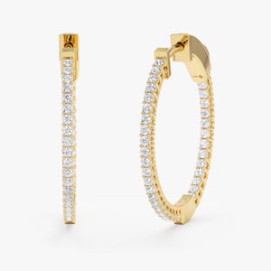 May include: A pair of gold hoop earrings with a row of small diamonds around the entire hoop.