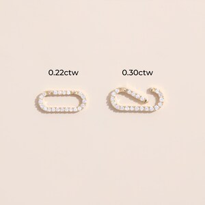 May include: Two gold oval-shaped earring charms with a row of clear cubic zirconia stones. The charm on the left is labeled "0.22ctw" and the charm on the right is labeled "0.30ctw".