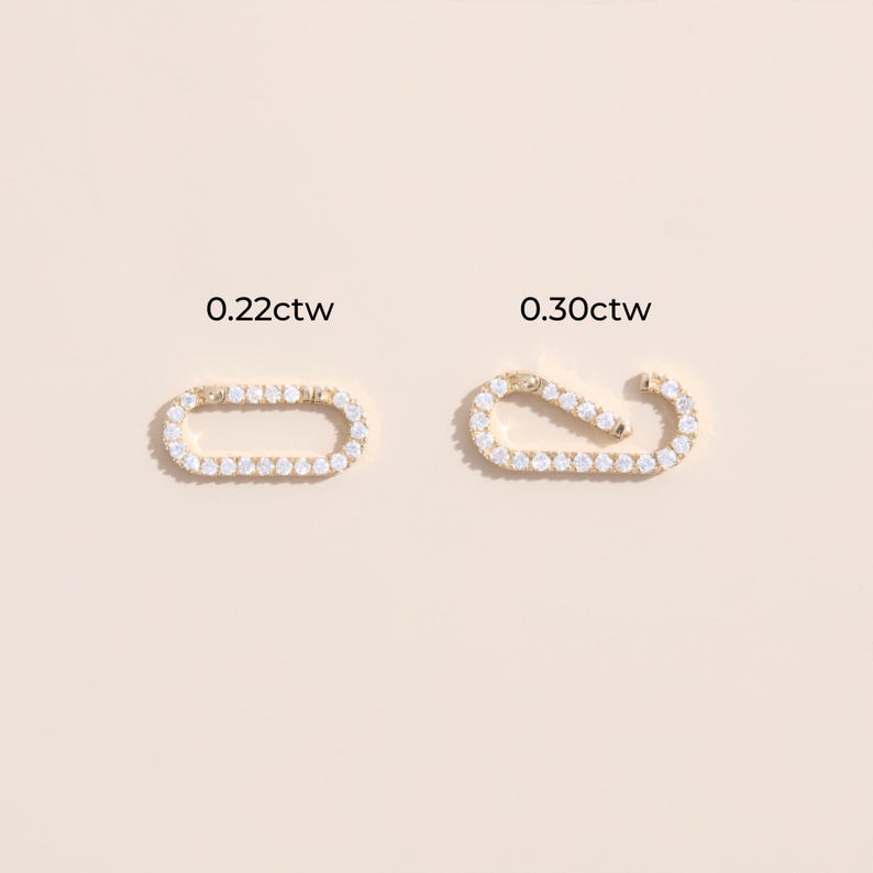 May include: Two gold oval-shaped earring charms with a row of clear cubic zirconia stones. The charm on the left is labeled "0.22ctw" and the charm on the right is labeled "0.30ctw".