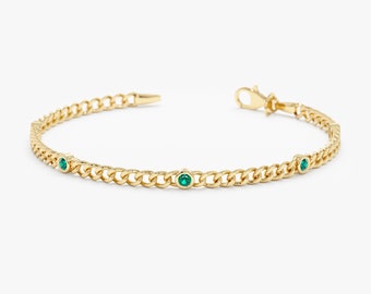 Peut inclure: Un bracelet en chaîne dorée avec de petites pierres précieuses vertes serties dans les maillons.
