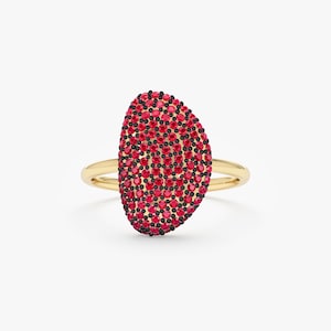 May include: A gold ring with a red and black oval-shaped stone. The stone is covered in small red and black gemstones.