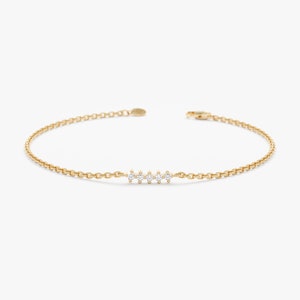 Op de afbeelding: Een delicate gouden kettingarmband met een rij kleine, heldere diamanten in het midden.