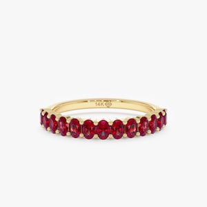 May include: A gold ring set with oval-cut red gemstones. The ring band is a thin, polished gold. The gemstones are evenly spaced around the band. The ring is labeled "14K".