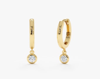May include: A pair of gold hoop earrings with a small diamond dangling from each hoop.