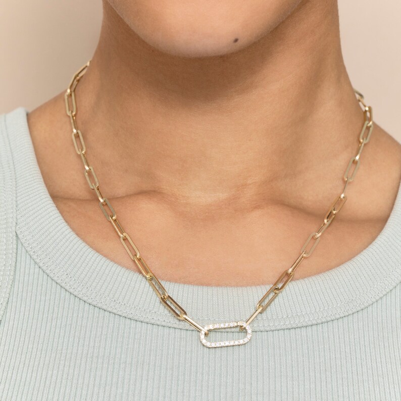 May include: A gold chain necklace with a large oval pendant set with small clear stones.