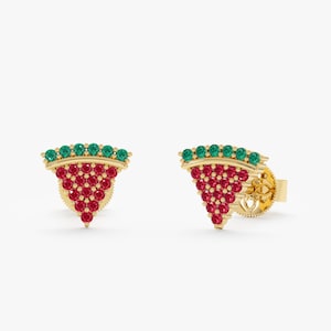 Puede incluir: Un par de pendientes dorados con forma de rodajas de sandía. Cada pendiente presenta una fila de piedras preciosas verdes en la parte superior, con un grupo de piedras preciosas rojas debajo, creando un diseño colorido con temática de frutas.