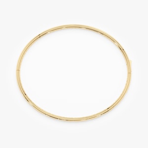 Puede incluir: Un brazalete de color dorado con un dise&ntilde;o sencillo y elegante. El brazalete es circular y parece estar hecho de metal. El cierre es visible en el lado derecho. La joya est&aacute; sobre un fondo blanco.