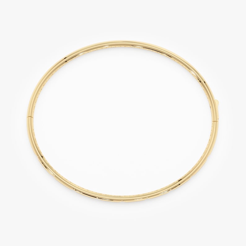 Puede incluir: Un brazalete de color dorado con un dise&ntilde;o sencillo y elegante. El brazalete es circular y parece estar hecho de metal. El cierre es visible en el lado derecho. La joya est&aacute; sobre un fondo blanco.