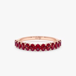 K&ouml;nnte beinhalten: Ros&eacute;goldener Ring mit einem Band aus oval geschliffenen, leuchtend roten Edelsteinen. Der Ring ist mit "14K" auf dem Band markiert. Die Edelsteine sind eng aneinander gesetzt.