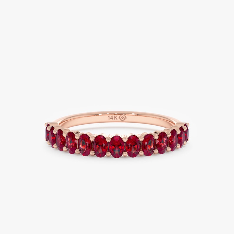 K&ouml;nnte beinhalten: Ros&eacute;goldener Ring mit einem Band aus oval geschliffenen, leuchtend roten Edelsteinen. Der Ring ist mit "14K" auf dem Band markiert. Die Edelsteine sind eng aneinander gesetzt.