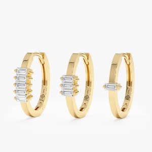 May include: Three gold hoop earrings with baguette-shaped diamonds. The earrings have a hinged closure and are marked "14K".