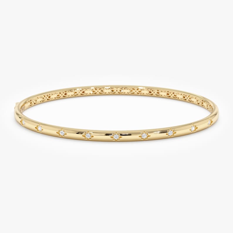 Puede incluir: Un brazalete dorado con detalles en forma de estrella y peque&ntilde;as gemas transparentes. El brazalete tiene un acabado liso y pulido y un patr&oacute;n decorativo cerca del cierre. Esta elegante joya es adecuada para el uso diario o para ocasiones especiales.