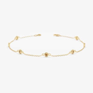 May include: A delicate gold chain bracelet with five small round bezel-set stones.