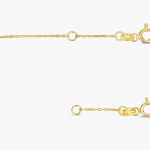 May include: Two gold chain extenders with a lobster clasp closure. The extenders are shown in a straight line, with the top extender slightly longer than the bottom extender.