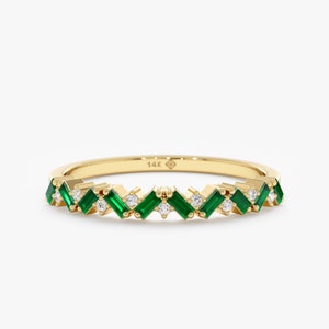 May include: A 14k gold band ring with a chevron pattern of emerald green and white gemstones.