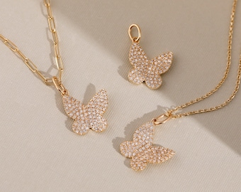 May include: Gold-toned butterfly pendant necklaces and a charm. The butterfly pendants are encrusted with small, sparkling stones. One necklace features a paperclip chain, while the others have delicate link chains. The jewelry is displayed on a neutral background.