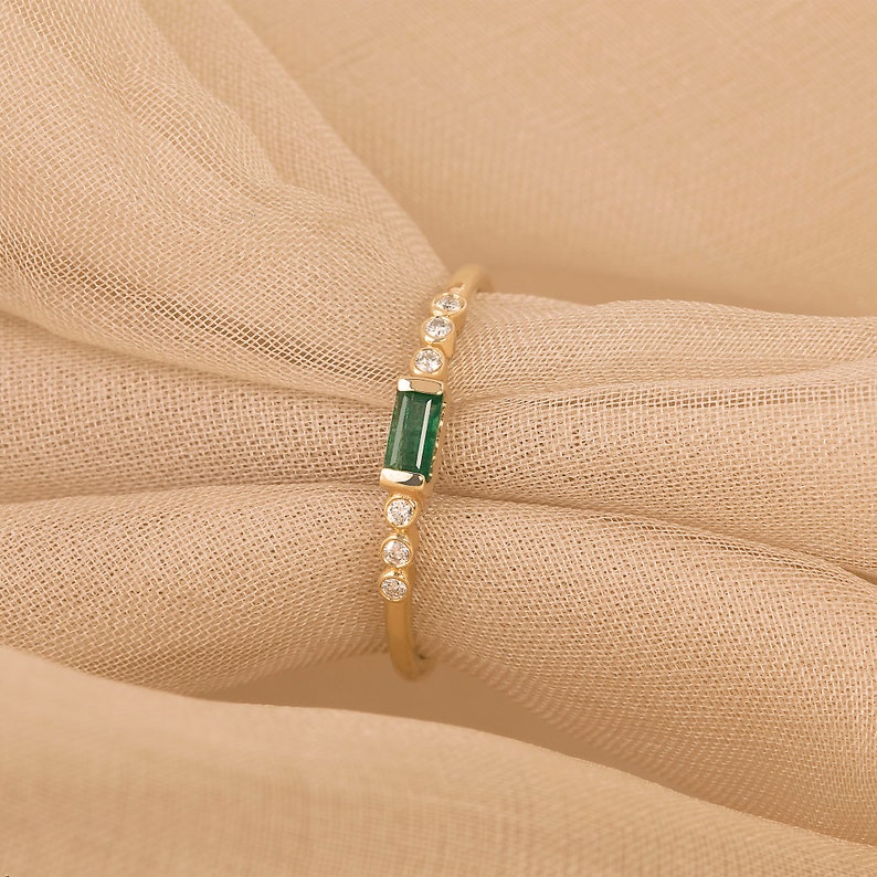 thin 14k gold ring with baguette-cut emerald and natural diamonds