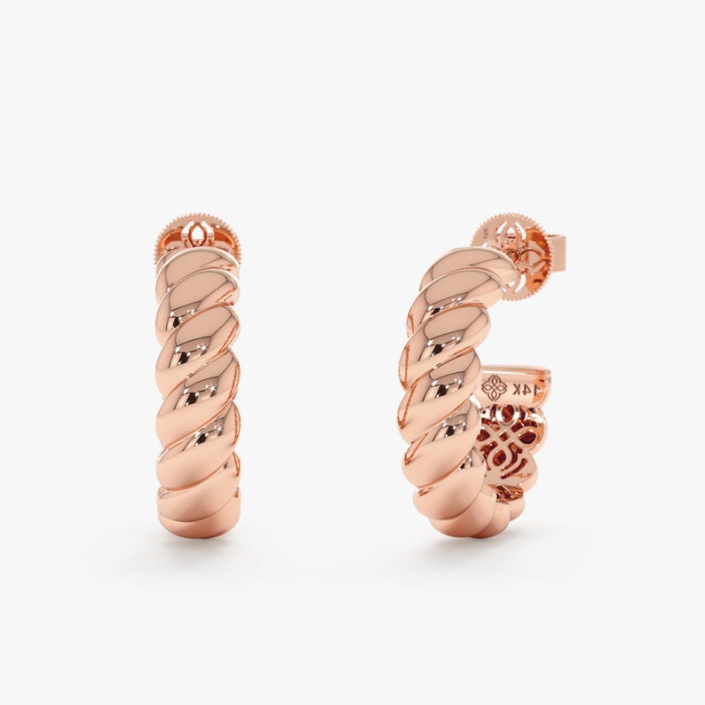 May include: Rose gold hoop earrings with a twisted rope design. The earrings have a post back closure and a polished finish. The earrings are a classic and elegant accessory.