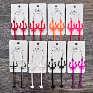 May include: Set of ten pairs of dangle earrings featuring a trident design. The earrings are made of acrylic and come in a variety of colors, including red, orange, pink, white, black, and purple.