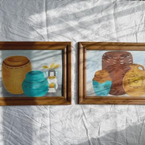 Puede incluir: Dos pinturas enmarcadas de cerámica nativa americana. Las pinturas están en marcos de madera con un acabado marrón claro. La primera pintura representa tres piezas de cerámica, una olla grande marrón con un diseño geométrico, una olla azul más pequeña con un diseño geométrico y una pequeña muñeca con un vestido azul y blanco. La segunda pintura representa tres piezas de cerámica, una olla grande marrón con un diseño geométrico, una olla azul más pequeña con un diseño geométrico y una olla amarilla más pequeña con un diseño geométrico.