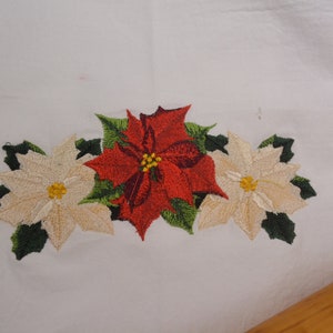 Puede incluir: Toalla de cocina blanca bordada con una flor de pascua roja y dos flores de pascua blancas.