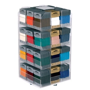 Op de afbeelding: Een transparante acryl displaystandaard met meerdere planken, elk met rijen kleine spoelen garen. De spoelen zijn geëtiketteerd met "SCANFIL" en zijn verkrijgbaar in verschillende kleuren, waaronder rood, blauw, groen, geel en wit.