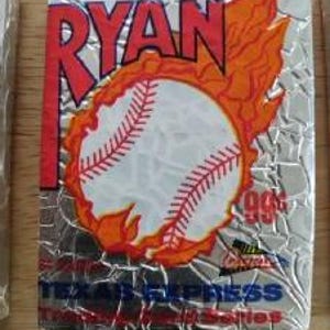 May include: A baseball card featuring Nolan Ryan with a baseball engulfed in flames. The card has a silver background with the text "Nolan Ryan" in red and the text "Texas Express" in blue. The card is from the 90s.