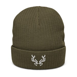 Op de afbeelding: Olijfgroene beanie met een geribbelde gebreide textuur. De hoed heeft een wit geborduurd geweimotief op de voorkant. Deze winteraccessoire is stijlvol voor koud weer.