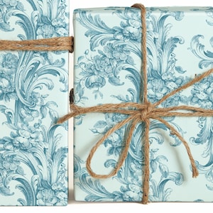 May include: Two gift boxes wrapped in blue and white floral patterned paper with twine bows.