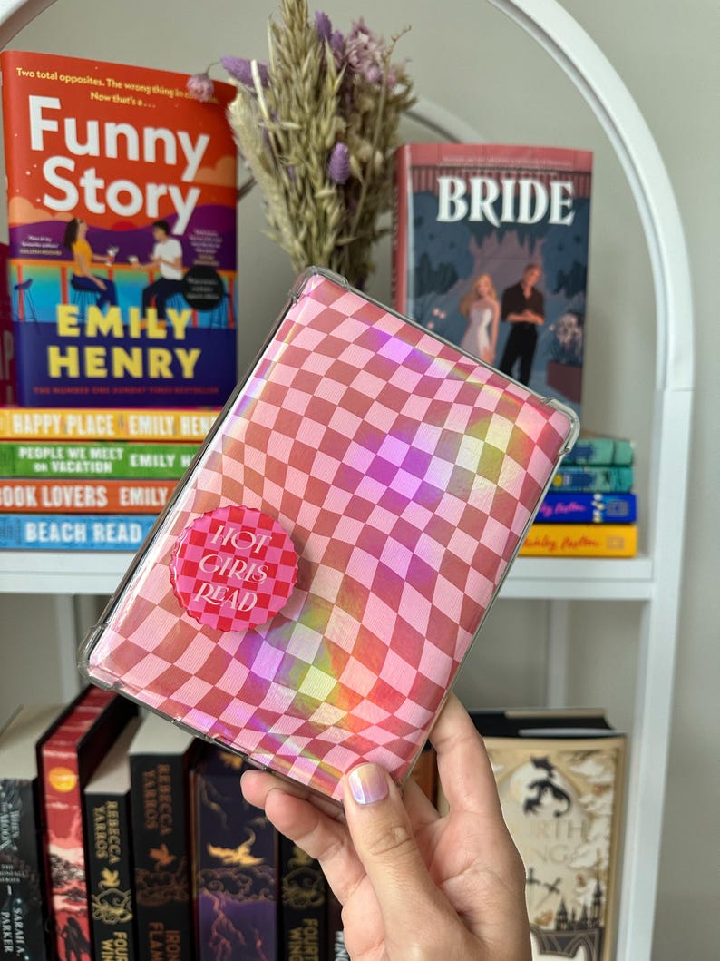 May include: A pink and white checkered book cover with a holographic effect. The cover has a pink button with the text "Hot Girls Read" on it.