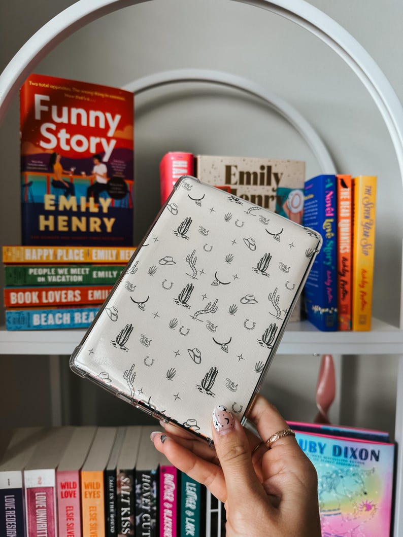 May include: A white phone case with a black and white pattern of cacti, stars, horseshoes, and cowboy hats.